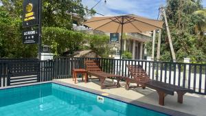 two chairs and an umbrella next to a swimming pool at Lotus Manuvala - Negombo in Kochchikade