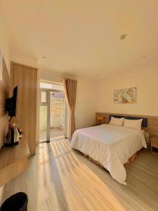 a bedroom with a large white bed and a television at Bee Luxury Dalat Hotel in Da Lat