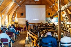 a woman standing in front of a screen in a room with a crowd at Håholmen - by Classic Norway Hotels in Karvåg