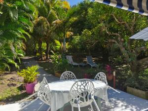 a table and chairs on a patio with palm trees at Gîte 1001 Nuits - SINBAD in Bouillante