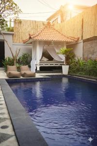 a swimming pool with a gazebo in a backyard at Homey Villa in Canggu