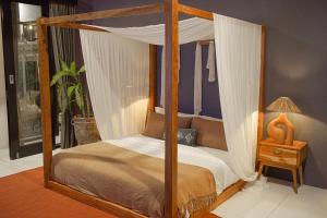 a bedroom with a four poster bed with a canopy at Homey Villa in Canggu +15 photos