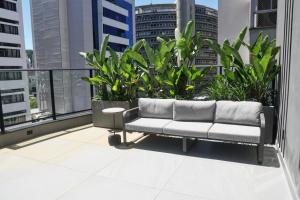 a couch sitting on top of a balcony with plants at Xtay Oslo Florianópolis - Residential studio 5 minutes from downtown, close to Epic School and Atlantis Executive Center in Florianópolis