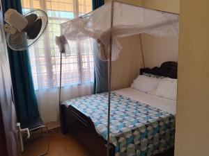 a bedroom with a canopy bed with a fan at milina homes in Ukunda