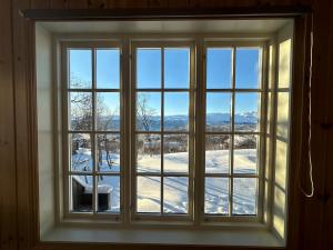 a window with a view of a snow covered yard at Koselig Gjestehus Med Badstue in Beitostøl