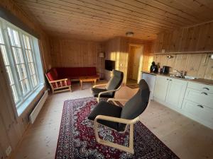 a living room with chairs and a table and a kitchen at Koselig Gjestehus Med Badstue in Beitostøl