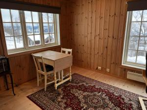 a room with a table and a chair and windows at Koselig Gjestehus Med Badstue in Beitostøl