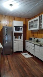 a kitchen with stainless steel appliances and wooden walls at Casa da Serra borrussia in Osório