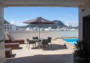 a patio with a table and chairs and an umbrella at Riale Vilamar Copacabana in Rio de Janeiro