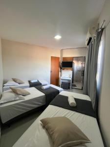 a hotel room with three beds and a kitchen at Casa Lua in Brumadinho