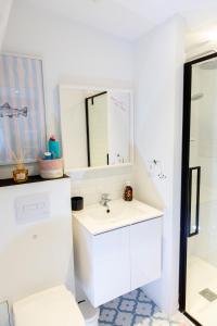 a white bathroom with a sink and a mirror at Beach House in Lège-Cap-Ferret +30 photos