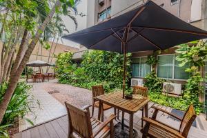 ein Tisch und Stühle mit einem Sonnenschirm auf einer Terrasse in der Unterkunft Hotel Maione in Goiânia + 87 Fotos