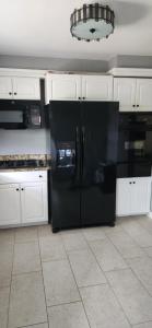 a black refrigerator in a kitchen with white cabinets at 3 Bedroom home near DC in Oxon Hill