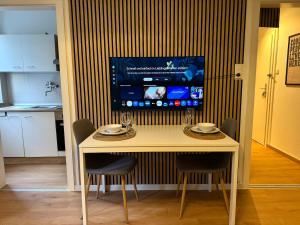 a kitchen with a table with chairs and a tv on the wall at Charmant, Zentrumsnah, Natur in Augsburg
