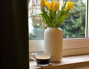 a vase with yellow flowers and a glass of coffee at Charmant, Zentrumsnah, Natur in Augsburg +4 photos