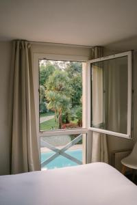 a bedroom window with a view of a palm tree at Hotel Aigue Marine in Tréguier