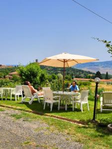 a group of people sitting around a table with an umbrella at I Castagnini in Montecatini Val di Cecina