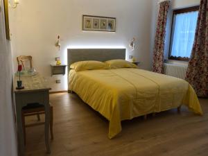a bedroom with a bed with a yellow bedspread at Agriturismo Casa Donazzolo in Pedavena +9 photos