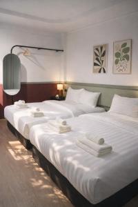 three beds in a hotel room with white sheets at Quicky Stay Airport in Min Buri