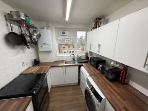 a kitchen with white cabinets and a washer and dryer at Birch House in London