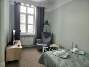 a bedroom with a bed and a chair and a television at Apartamenty u Antka in Nowe Miasto Lubawskie