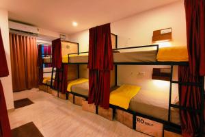 a room with four bunk beds with red curtains at Mitra Palolem in Palolem