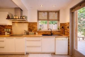 a kitchen with white cabinets and a window at - Chalet Cosy - Pleine nature in Lagnieu +10 photos