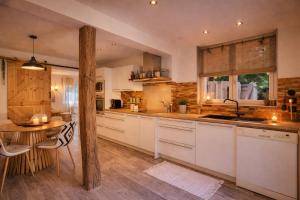 a kitchen with white cabinets and a wooden table at - Chalet Cosy - Pleine nature in Lagnieu