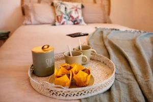 a tray with food and cups on a bed at - Chalet Cosy - Pleine nature in Lagnieu