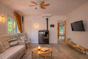 a living room with a couch and a tv at - Chalet Cosy - Pleine nature in Lagnieu