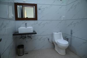 a bathroom with a toilet and a sink and a mirror at Ayushman hotel in Uttarkāshi