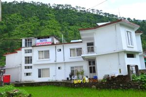 a white building with a sign on top of it at Ayushman hotel in Uttarkāshi