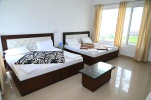 two beds in a room with a window at Ayushman hotel in Uttarkāshi