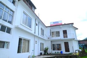 a white building with a hotel ambassador sign on it at Ayushman hotel in Uttarkāshi