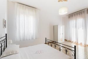 a white bedroom with two beds and windows at Paco House in Avola