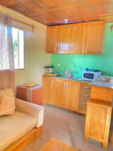 a kitchen with wooden cabinets and a couch in a room at Nid douillet kribi in Kribi