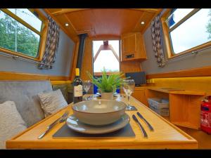 a table with a bowl and a wine glass on it at Dylan, 43ft Narrowboat with Garden in North Newton