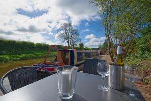 a table with a bottle of wine and two glasses at Dylan, 43ft Narrowboat with Garden in North Newton