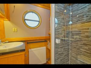 a bathroom with a shower and a sink and a mirror at Dylan, 43ft Narrowboat with Garden in North Newton
