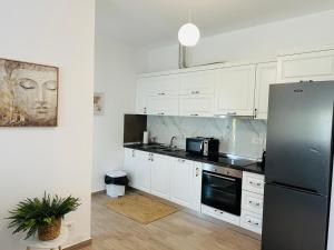 a kitchen with white cabinets and a stainless steel refrigerator at Valamar Deluxe Beachfront Villa in Draç