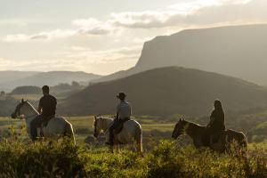 a group of three people riding horses in a field at Pousada Velho Chico in Vargem Bonita