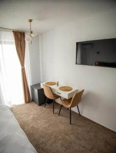 a room with a table and chairs and a bed at Moment Residence Sebes in Sebeş