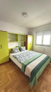 a bedroom with a large bed with green and yellow cabinets at Apartman Green in Lukavica
