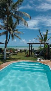 a swimming pool with a hammock and a view of the ocean at Maré Suítes Maragogi in Maragogi +49 photos