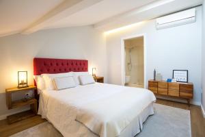 a bedroom with a large white bed with a red headboard at Metro Loft in Póvoa de Varzim