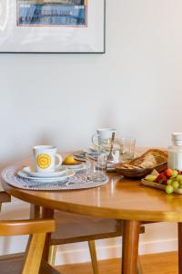 a table with coffee cups and bread on it at Metro Loft in Póvoa de Varzim