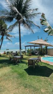 a group of tables and umbrellas next to a pool at Maré Suítes Maragogi in Maragogi