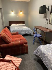 a room with two beds and a desk and a couch at Four Stars Hotel in London
