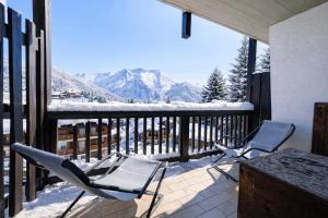 two chairs and a table on a balcony with snow covered mountains at Hostdomus - Pastore Apartment in Sestriere