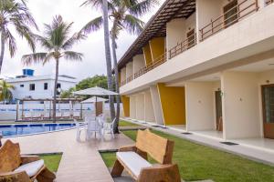 a resort with a swimming pool and palm trees at Pousada Paraiso da Barra in Barra de Santo Antônio